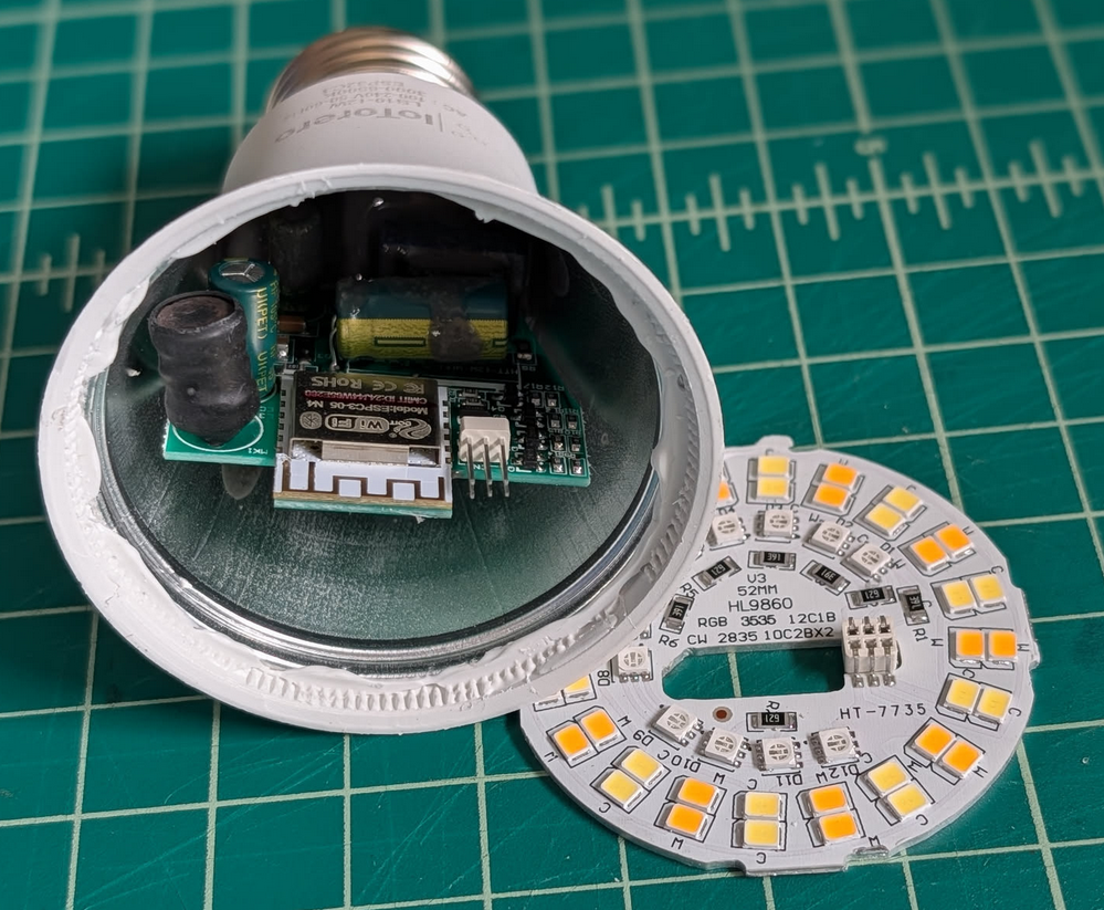 Light bulb with daughter board placed to the side. ESP32 revealed inside.